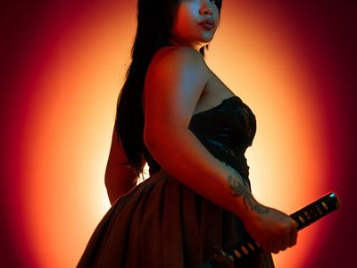 A silhouette of a woman in a strong warrior yoga pose against a soft background.