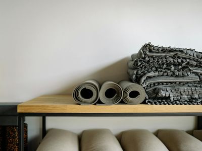 Peaceful studio corner with rolled up yoga mats and soft natural light.